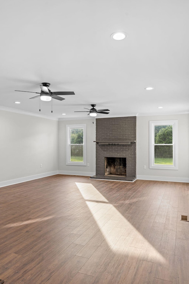 unfurnished living room featuring crown molding, light hardwood / wood-style flooring, ceiling fan, and a brick fireplace