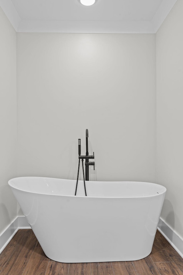 bathroom featuring a tub to relax in, ornamental molding, and hardwood / wood-style floors