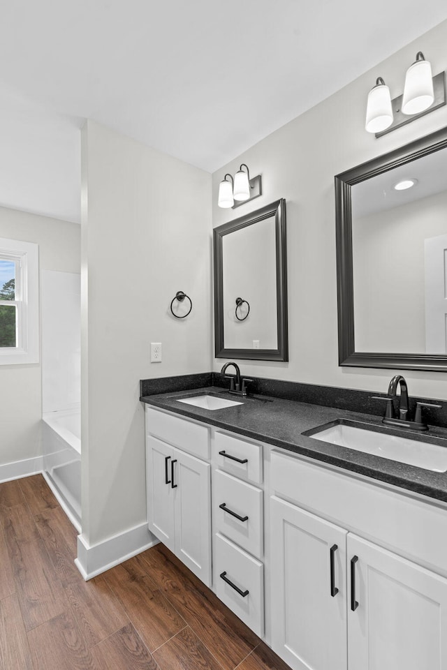 bathroom with wood-type flooring, a bathing tub, and vanity