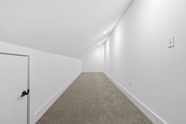 hallway with carpet flooring and vaulted ceiling