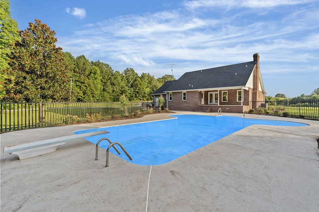 view of swimming pool with a diving board and a patio area