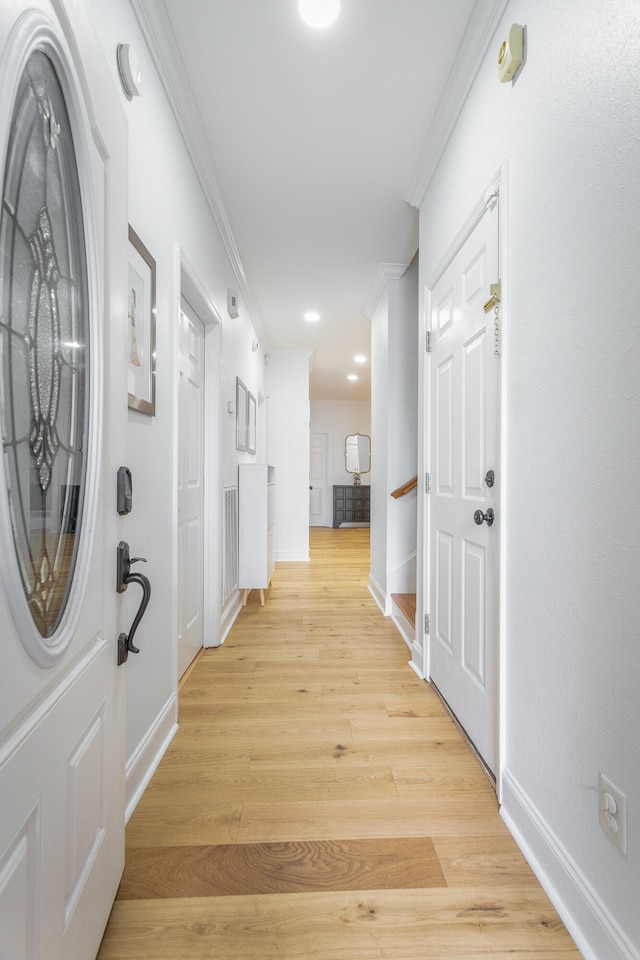 entrance foyer with ornamental molding and light hardwood / wood-style flooring