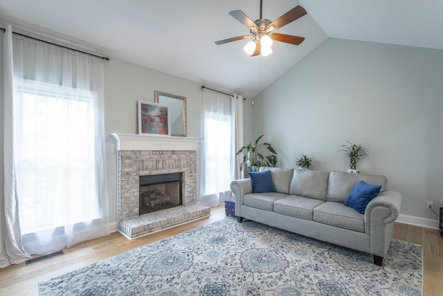 living room featuring lofted ceiling, ceiling fan, a fireplace, and light hardwood / wood-style floors