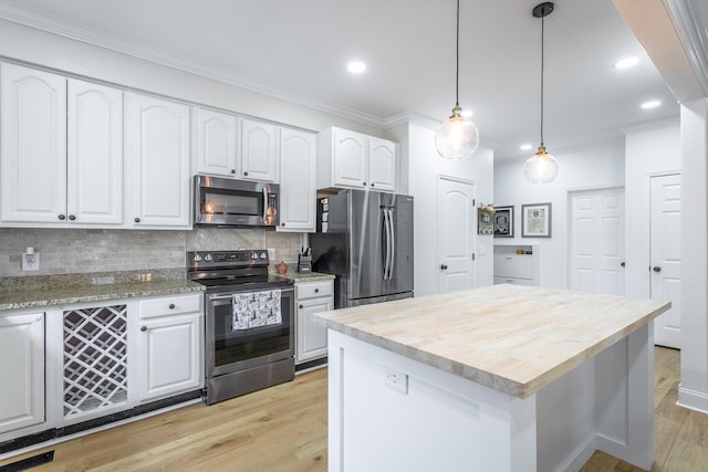 kitchen with hanging light fixtures, light wood-type flooring, appliances with stainless steel finishes, white cabinetry, and a kitchen island