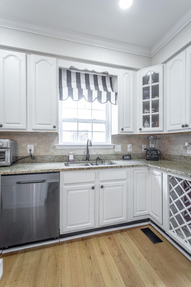 kitchen with light hardwood / wood-style floors, crown molding, stainless steel dishwasher, sink, and white cabinets