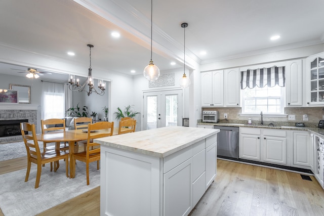 kitchen with light wood-type flooring, a healthy amount of sunlight, a kitchen island, and stainless steel dishwasher