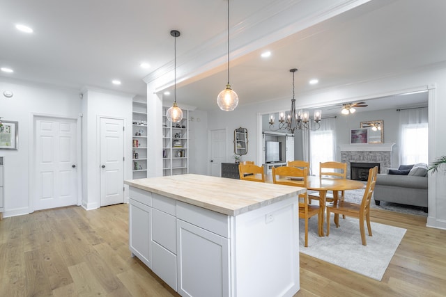 kitchen featuring a fireplace, light hardwood / wood-style flooring, a kitchen island, and ceiling fan