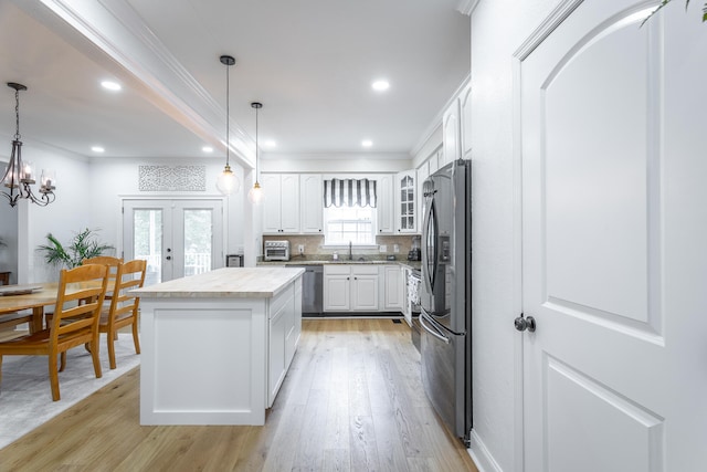 kitchen with white cabinetry, a wealth of natural light, a kitchen island, and light hardwood / wood-style floors