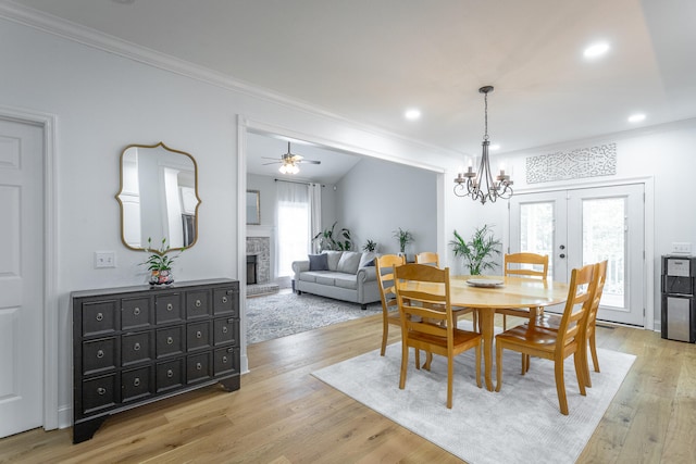 dining area with ceiling fan with notable chandelier, ornamental molding, and light hardwood / wood-style flooring