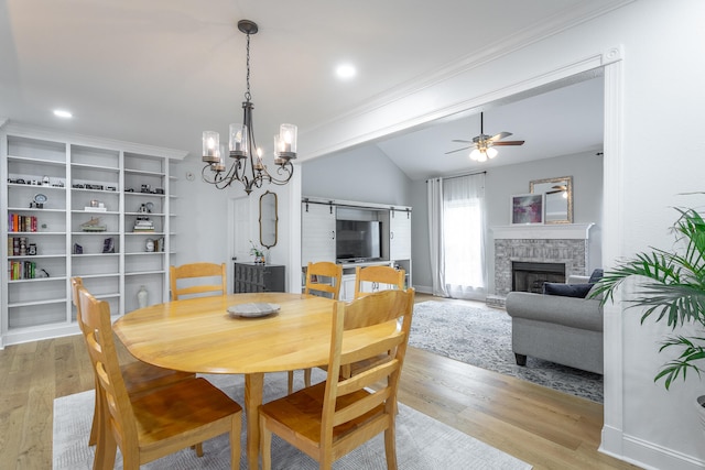 dining space featuring crown molding, light hardwood / wood-style flooring, vaulted ceiling, and ceiling fan with notable chandelier