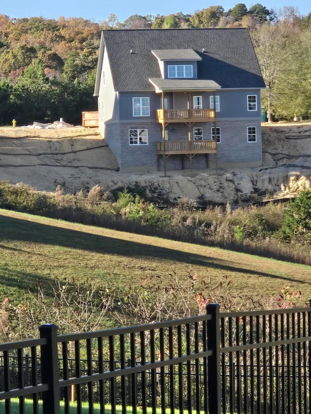 rear view of property featuring a yard and a balcony