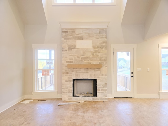 unfurnished living room with a fireplace, high vaulted ceiling, and a healthy amount of sunlight