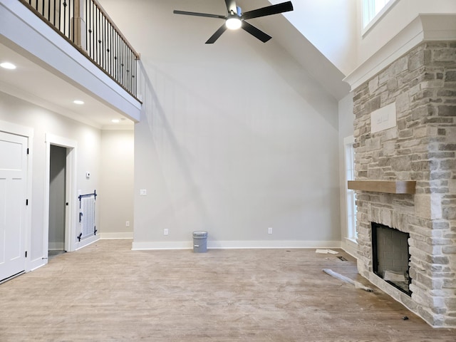 unfurnished living room featuring a fireplace, a towering ceiling, and light wood-type flooring