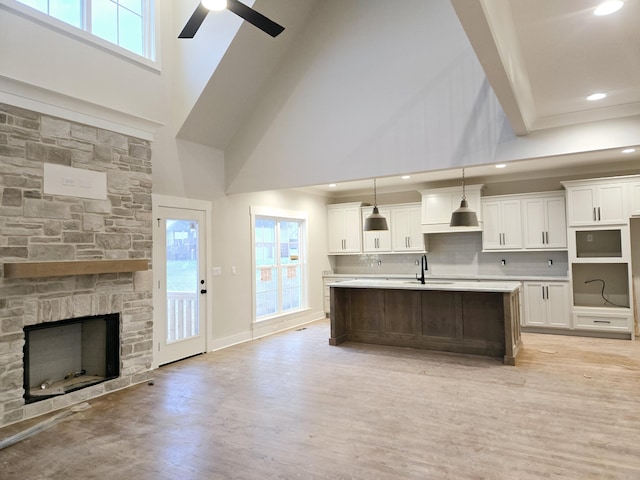 kitchen with tasteful backsplash, sink, white cabinets, a high ceiling, and hanging light fixtures