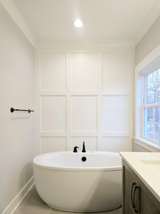 bathroom with tile patterned floors, vanity, ornamental molding, and a tub