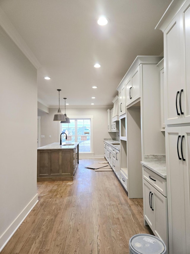 kitchen with white cabinets, sink, an island with sink, and hanging light fixtures