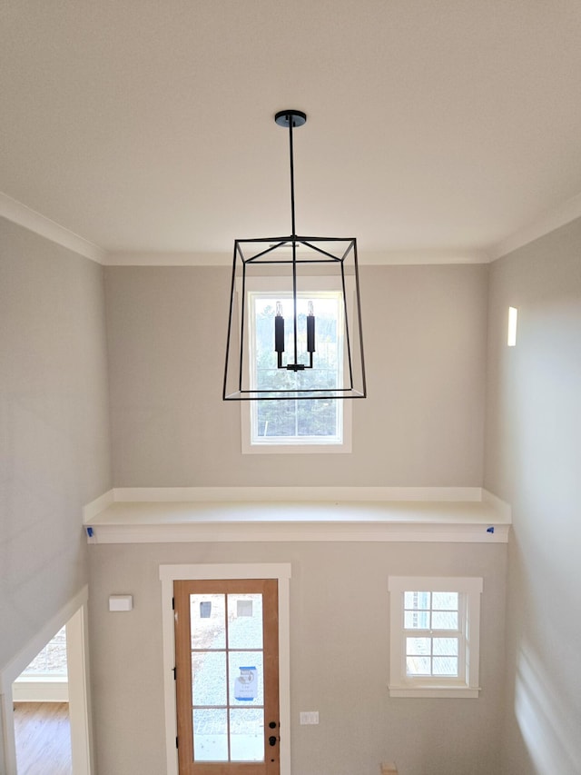 foyer entrance with ornamental molding and a chandelier