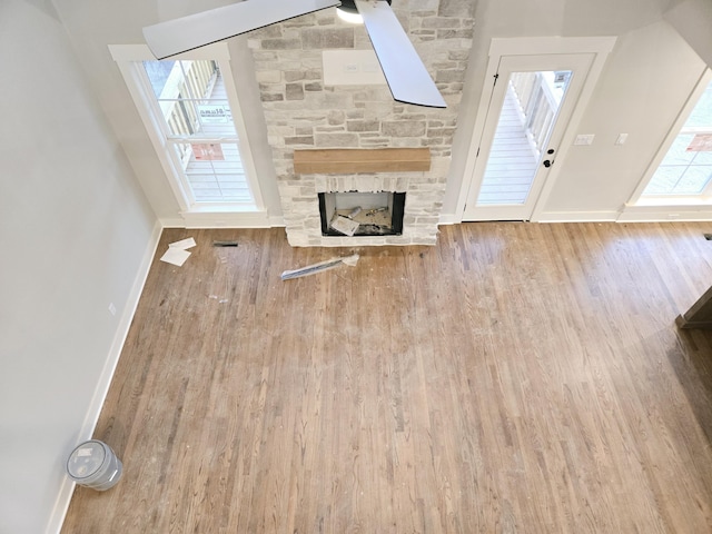 unfurnished living room with hardwood / wood-style flooring and a stone fireplace