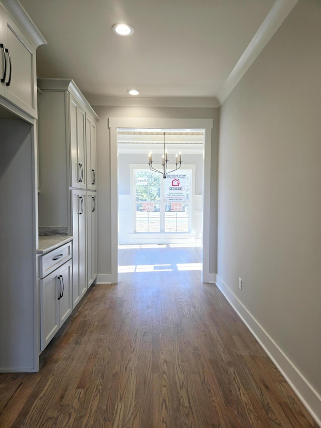 interior space featuring ornamental molding, dark hardwood / wood-style floors, and a chandelier