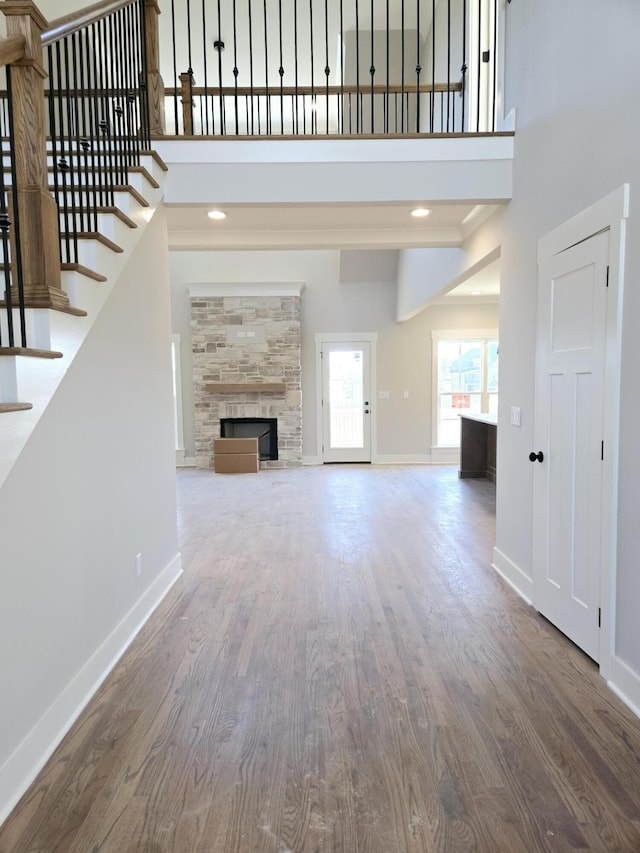 unfurnished living room featuring a towering ceiling, wood-type flooring, and a tile fireplace