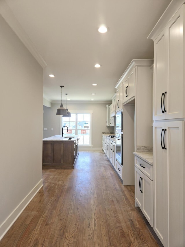 kitchen featuring a kitchen island with sink, oven, sink, and white cabinets