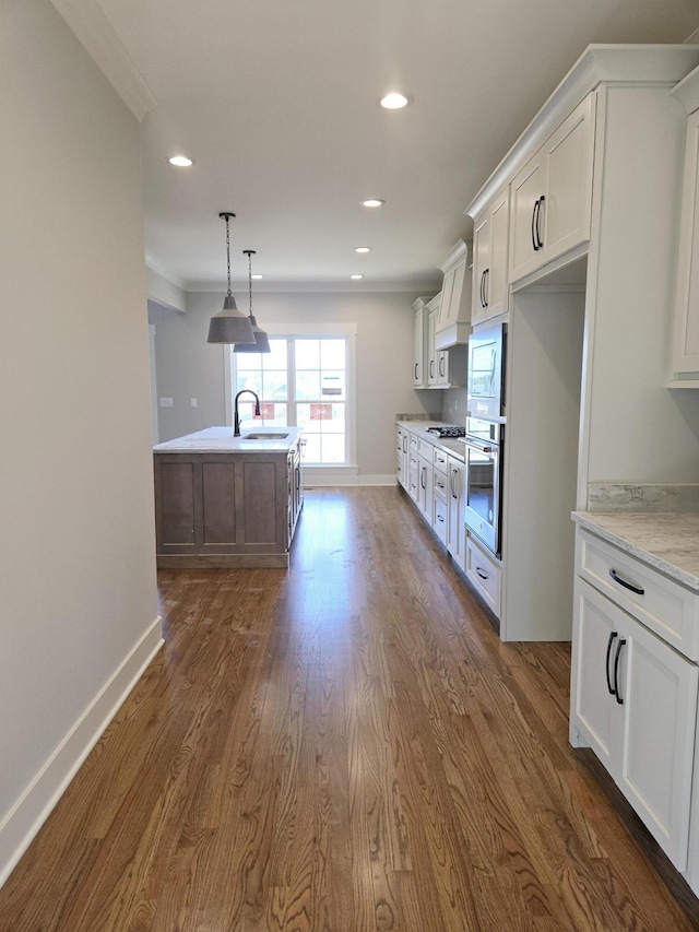 kitchen with white cabinetry, recessed lighting, stainless steel oven, and a sink
