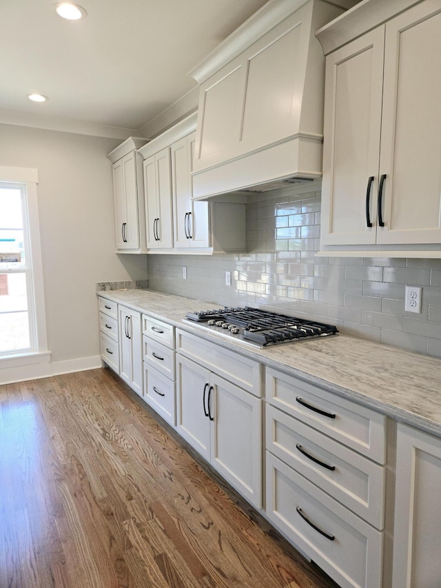 kitchen featuring dark wood finished floors, stainless steel gas stovetop, custom range hood, and backsplash