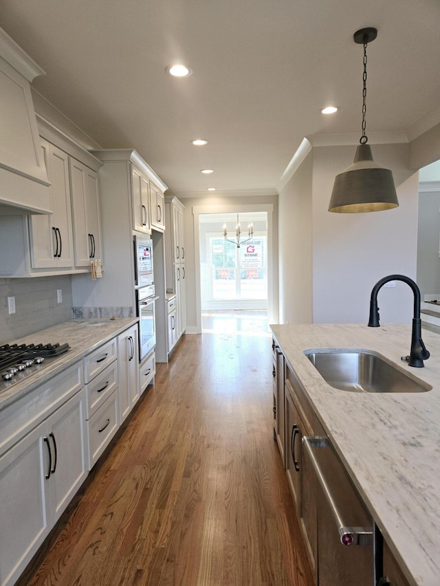 kitchen featuring recessed lighting, light stone countertops, a sink, dark wood-style flooring, and decorative light fixtures