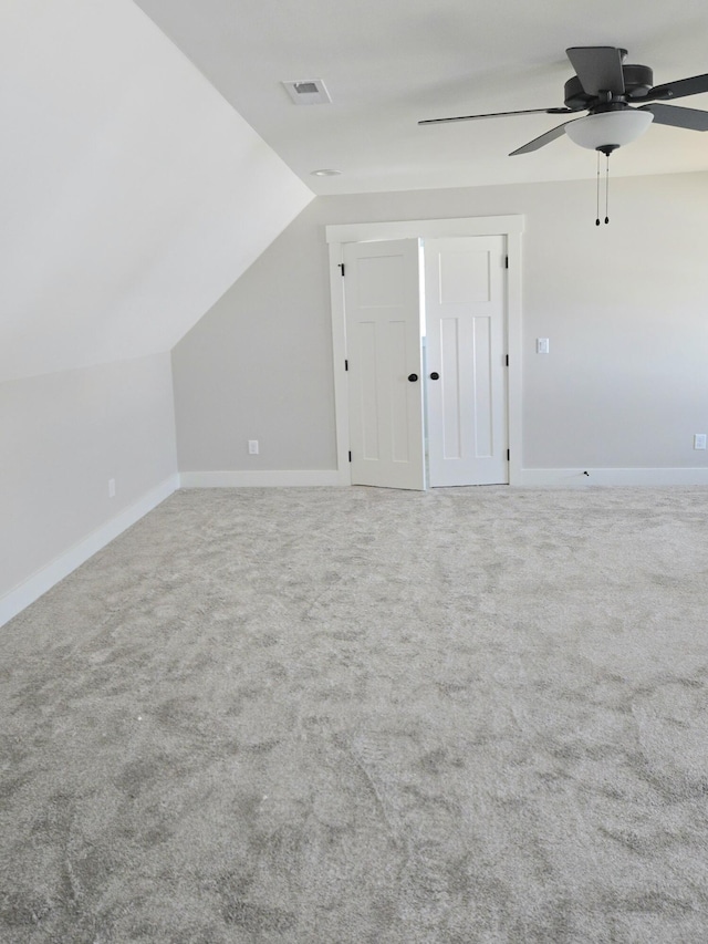additional living space with carpet flooring, ceiling fan, visible vents, vaulted ceiling, and baseboards