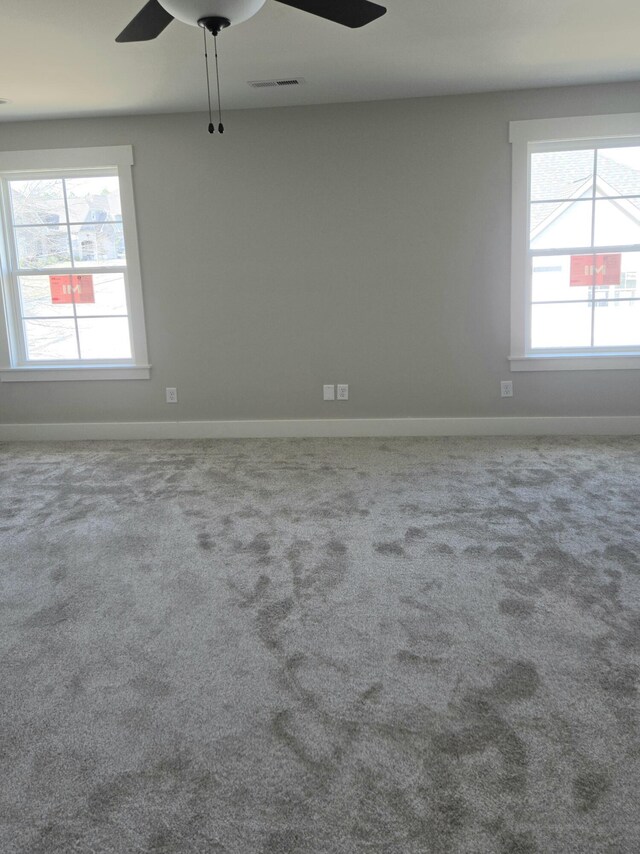 empty room with ceiling fan, baseboards, carpet floors, and visible vents