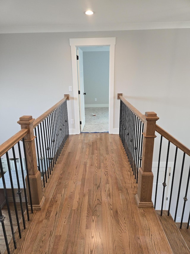 hall featuring recessed lighting, wood finished floors, ornamental molding, an upstairs landing, and baseboards