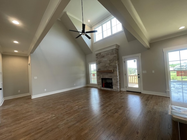 unfurnished living room featuring dark wood-style floors, a wealth of natural light, a fireplace, and ceiling fan