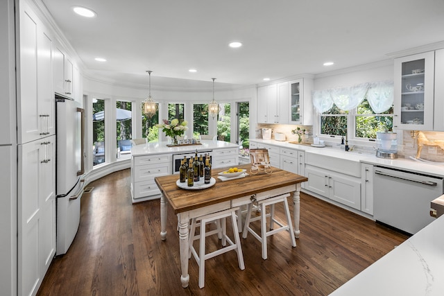 kitchen with a wealth of natural light, dark hardwood / wood-style flooring, white appliances, and white cabinets