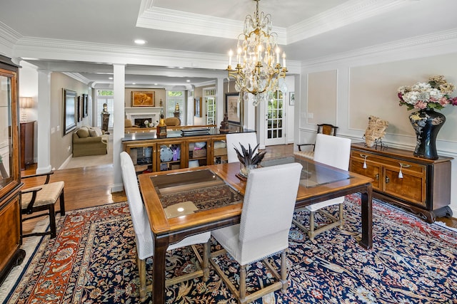 dining space featuring hardwood / wood-style floors, decorative columns, a wealth of natural light, and a chandelier