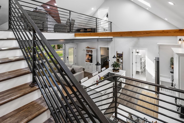 stairway with hardwood / wood-style floors and high vaulted ceiling