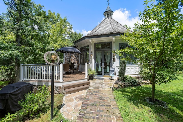 view of exterior entry with french doors, a yard, and a wooden deck