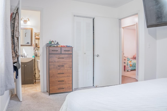 bedroom featuring a closet, light carpet, a sink, and ensuite bathroom