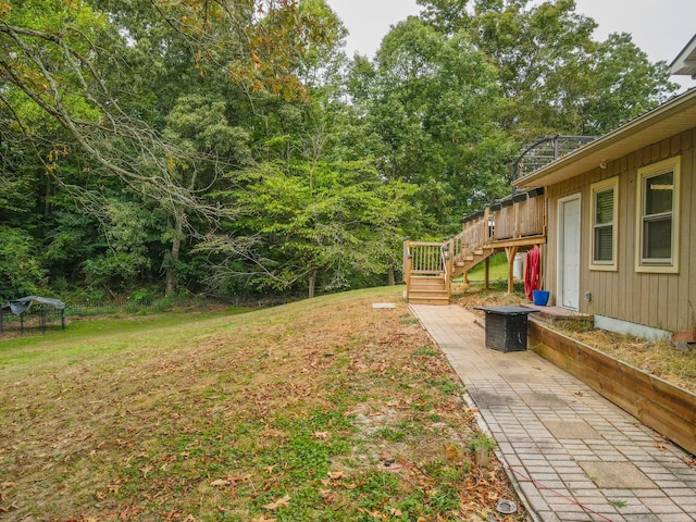 view of yard featuring a wooden deck, stairway, and a patio