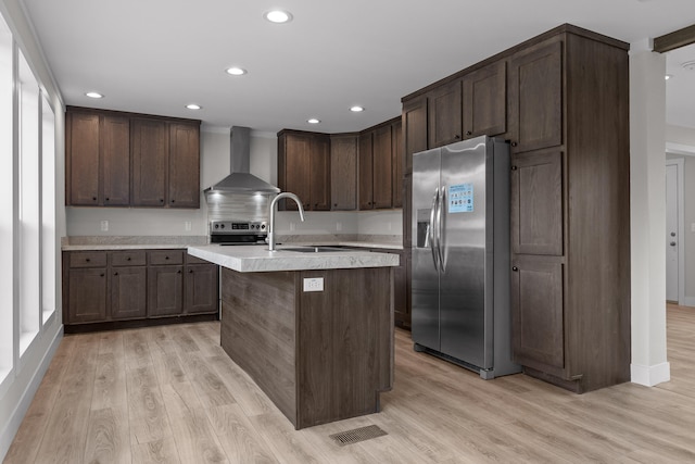 kitchen featuring dark brown cabinetry, sink, wall chimney exhaust hood, appliances with stainless steel finishes, and light wood-type flooring