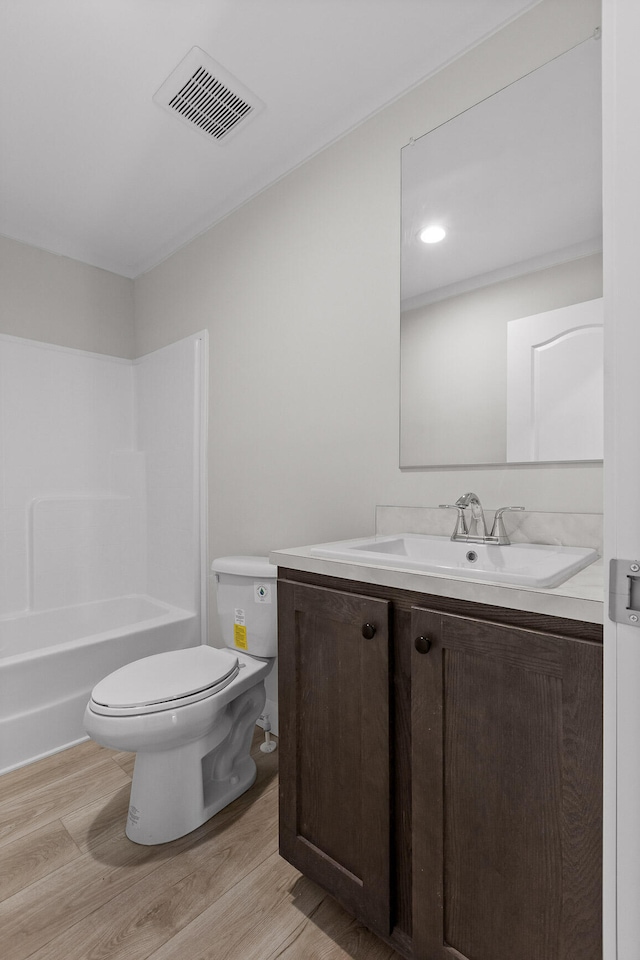 full bathroom featuring hardwood / wood-style floors, vanity, toilet, and shower / washtub combination