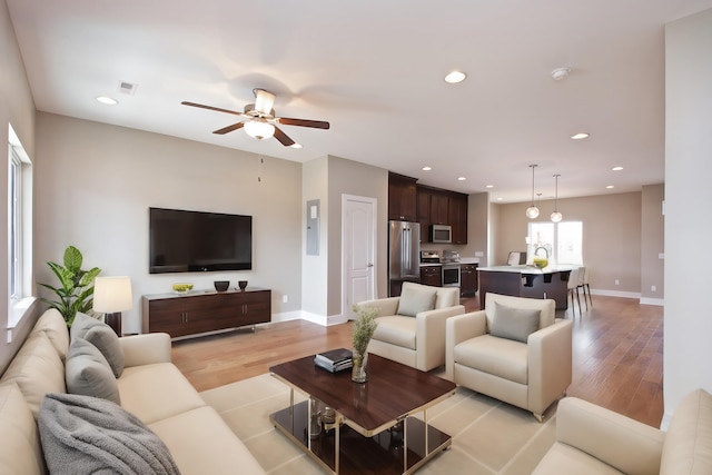 living room with light hardwood / wood-style flooring, electric panel, and ceiling fan