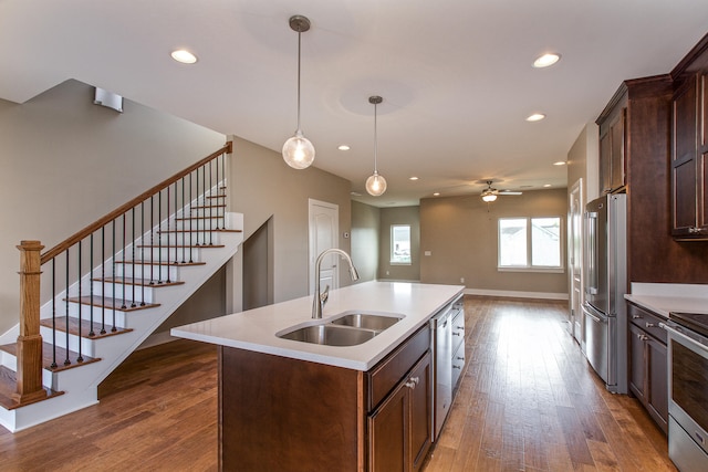 kitchen with a kitchen island with sink, sink, ceiling fan, dark hardwood / wood-style floors, and appliances with stainless steel finishes