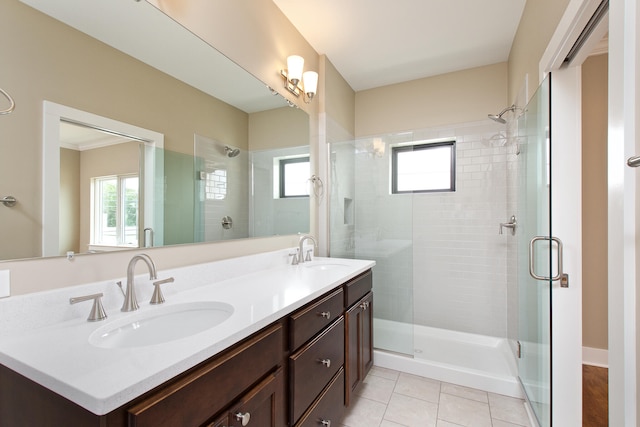 bathroom with a wealth of natural light, vanity, a shower with shower door, and tile patterned floors