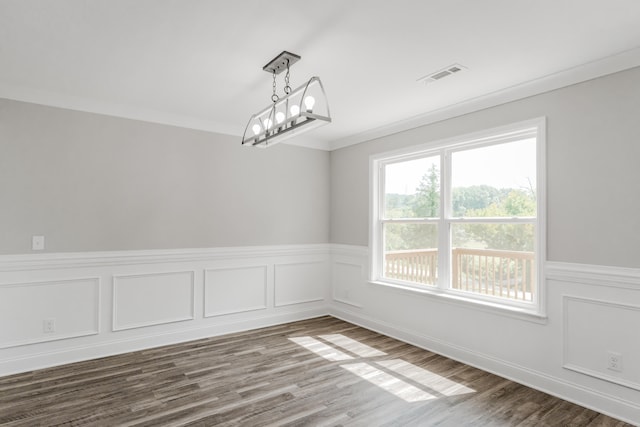 spare room with a notable chandelier, dark hardwood / wood-style floors, and ornamental molding