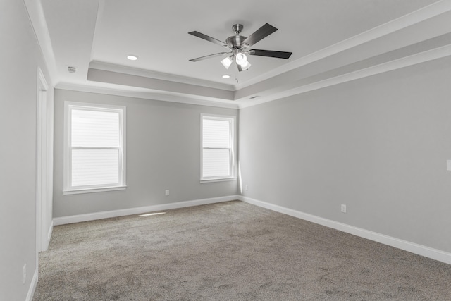 carpeted empty room featuring ceiling fan, a raised ceiling, and crown molding