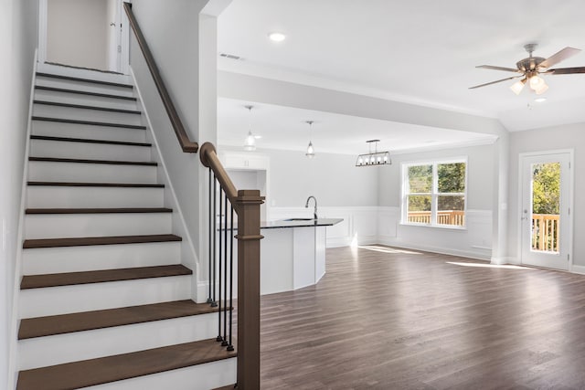 staircase with wood-type flooring, crown molding, sink, and ceiling fan