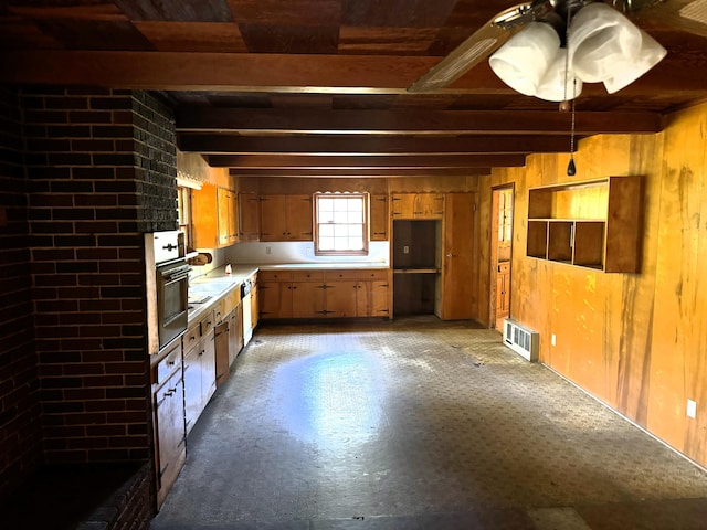 kitchen with wall oven, wooden walls, and beamed ceiling