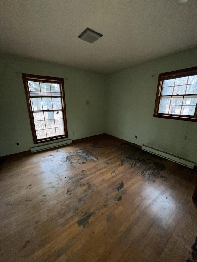 empty room featuring dark hardwood / wood-style flooring and a baseboard radiator