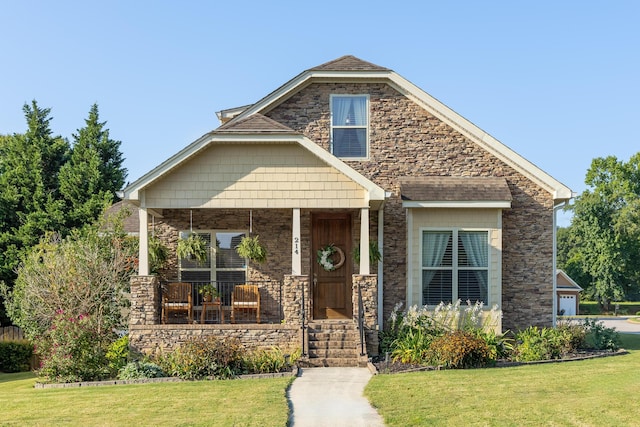 view of front of house with stone siding, covered porch, and a front yard