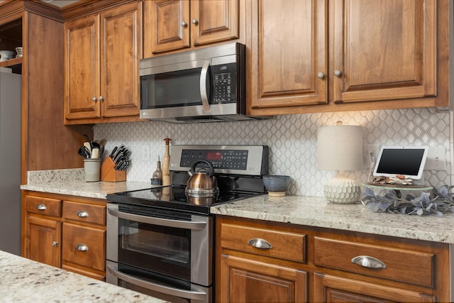 kitchen with appliances with stainless steel finishes, backsplash, and light stone countertops